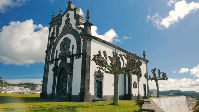 Panning shot of the Ermida de Nossa Senhora Mae de Deus in Ponta Delgada, The Azores, Portugal against a blue sky. 