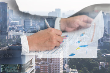 Double exposure of businessman hand hold a pen write, review document, cityscape and urban in the foggy morning as business and working concept. © ImagineDesign