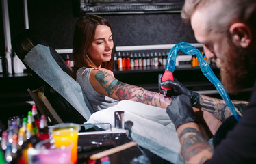 Professional tattoo artist makes a tattoo on a young girl's hand.