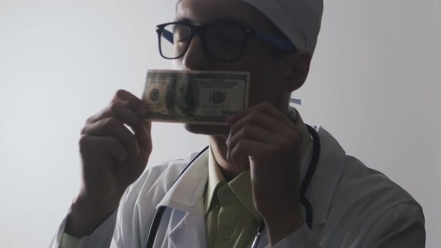 The doctor kisses a 100 dollar bill. A bribe to a medical worker. Expensive medicine.