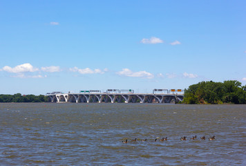 Woodrow Wilson Memorial Bridge across Potomac River photographed from the National Harbor, Maryland, USA. City infrastructure and nature on a summer day.