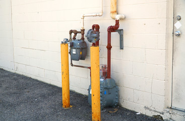 old gas meter installed outside the building with protection poles