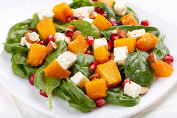 Salad of spinach leaves, baked pumpkin and feta cheese with almonds and pomegranate seeds