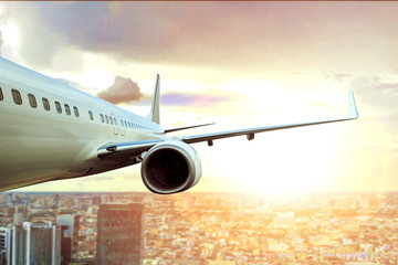 passenger plane flying over city building and sun light on background