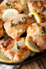 Fillet chicken piccata with lemon, thyme and capers close-up. vertical
