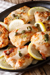 Italian chicken piccata with sauce, lemon and capers close-up. Vertical