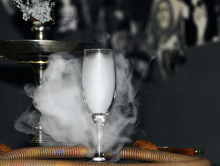 Heavy hookah smoke in a glass on a gray background, hookah tube