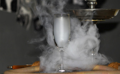 Heavy hookah smoke in a glass on a gray background, hookah tube