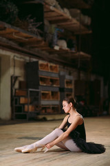 Fototapeta na wymiar Young ballerina in black dress trains behind the scenes.