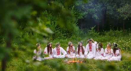 Midsummer. Young people in Slavic clothes sitting in the woods near the fire.
