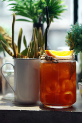 Glass of Iced tea with lemon slice topped with orange and rosemary leaves on blurred background, Selective focus.