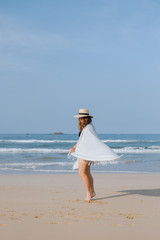 Fototapeta na wymiar Girl in a hat and a plaid walks along the beach 