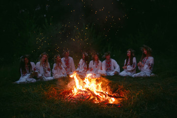 Fototapeta na wymiar Midsummer night. Young people in Slavic clothes sitting near the bonfire.
