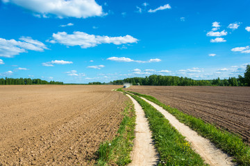 Fototapeta na wymiar Rural road between two plowed fields.