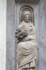 Statue on facade of old building, woman with a bouquet of flowers, Prague, Czech Republic.