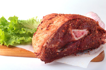 Raw pork knuckle, garlic, spices and lettuce leaves on a cutting board. Selective focus. Ready for cooking.