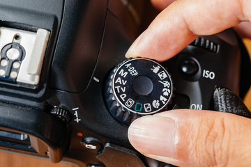 Av dial mode on dslr camera with fingers on the dial