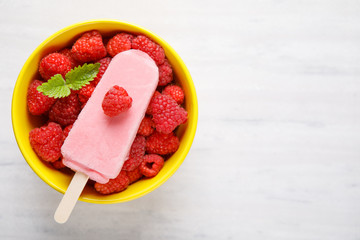 Raspberry ice cream popsicles in yelow bowls with raspberry fruit