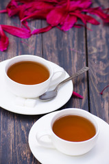 Hot tea and peony petals on dark