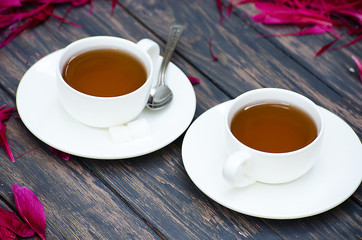 Hot tea and peony petals on dark