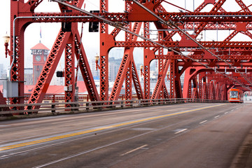 Red Broadway Bridge over Willamette River in Portland center with modern tram