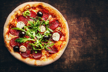 Hot pizza slice with salami, olives and cheese on a rustic wooden table. Top view. Fresh Pizza on...