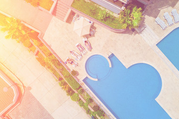 People lying on the sun loungers near the pool in the sunlight, top view