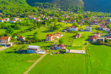 Top view of the village houses with red tiled roof on the green grass