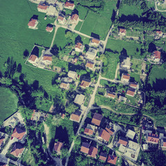 Top view of the village houses with red tiled roof on the green grass. Toned
