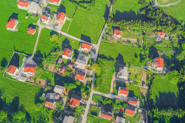Fototapeta premium Top view of the village houses with red tiled roof on the green grass
