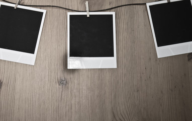 three blank instant photos hanging on clothesline on wooden background, art concept