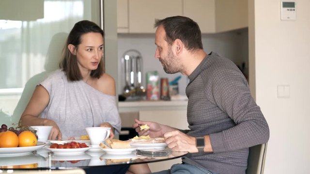 Young couple talking during breakfast at home
