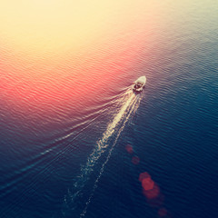 Top view of a white boat sailing in the blue sea on a sunny day