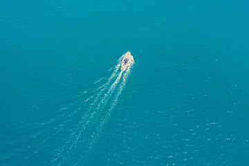 Obraz premium Top view of a white boat sailing in the blue sea