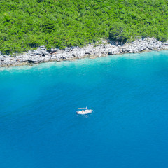 Fototapeta na wymiar Man aboard a white boat in the sea near a green shore
