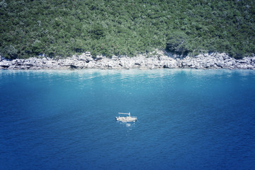White boat floating near a rocky shore