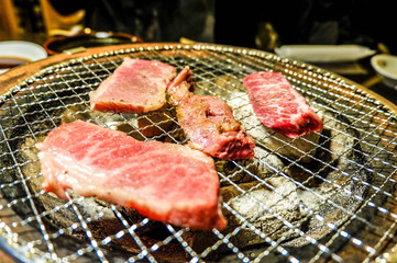 Grilled beef slide almost ready on the grill with metal tongs.