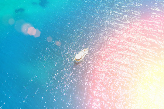 Top view of a white boat in the blue sea in the sunlight
