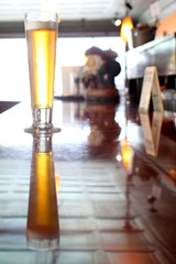 A pilsner beer on the counter of a bar.