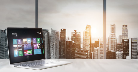 Laptop on table in office with panoramic sunset view of modern downtown skyscrapers at business district - obrazy, fototapety, plakaty