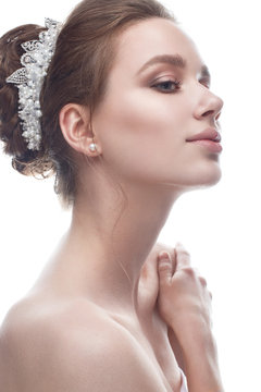 A young girl in a gentle wedding image with a diadem on her head. Beautiful model in the image of the bride on a white isolated background with nude makeup. Pure shining skin. Beauty of the face.