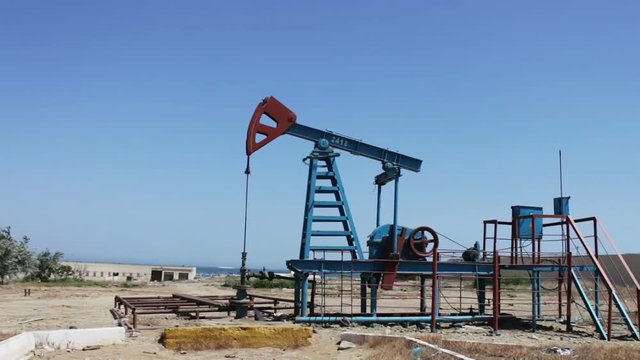 Oil pumpjacks in a working oil field in Baku, Azerbaijan.Silhouette of working oil pump on a background of blue sky and clouds.Oil fields