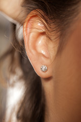 Closeup female ear with a small luxurious earring