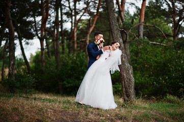 Beautiful young wedding couple admiring each other in a pine tree forest.