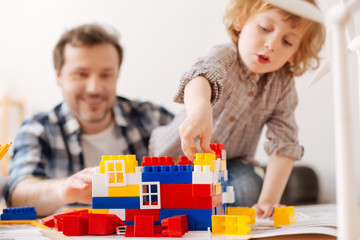 Infatuated boy with opened mouth playing with toys