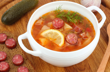  saltwort russian beef, pork and sausage soup solyanka with lemon, salami in plate on wood background