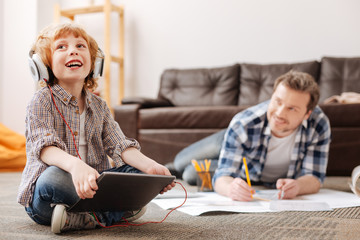 Positive delighted boy holding tablet in both hands