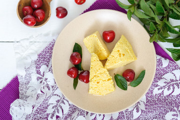 Air milky-vanilla pudding with ripe cherries and mint leaves on a plate. Dessert of Brazilian cuisine.The top view