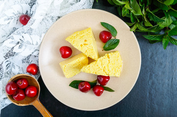 Air milky-vanilla pudding with ripe cherries and mint leaves on a plate. Dessert of Brazilian cuisine.