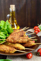 Lula-kebab is a meat dish, traditional for the Caucasus, in Central Asia and Turkey. Minced meat strung on a skewer and fried. Serve on a plate with lettuce leaves and fresh tomatoes. Vertical view